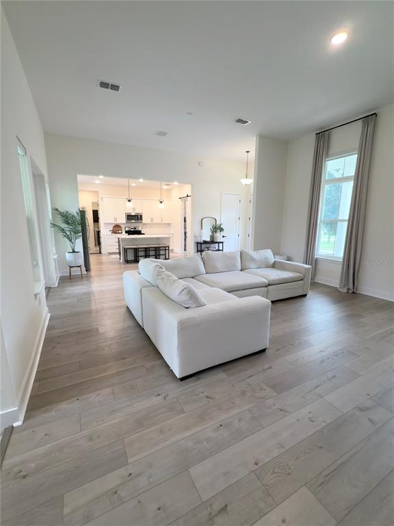 A bright living room with light wood floors features a large white sectional sofa — 310 W WASHINGTON AVENUE, LAKE HELEN, FL