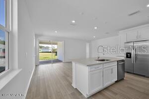 A modern kitchen with a white island and stainless steel appliances opens to a living area — 326 FISHTAIL PLACE, PALM COAST, FL