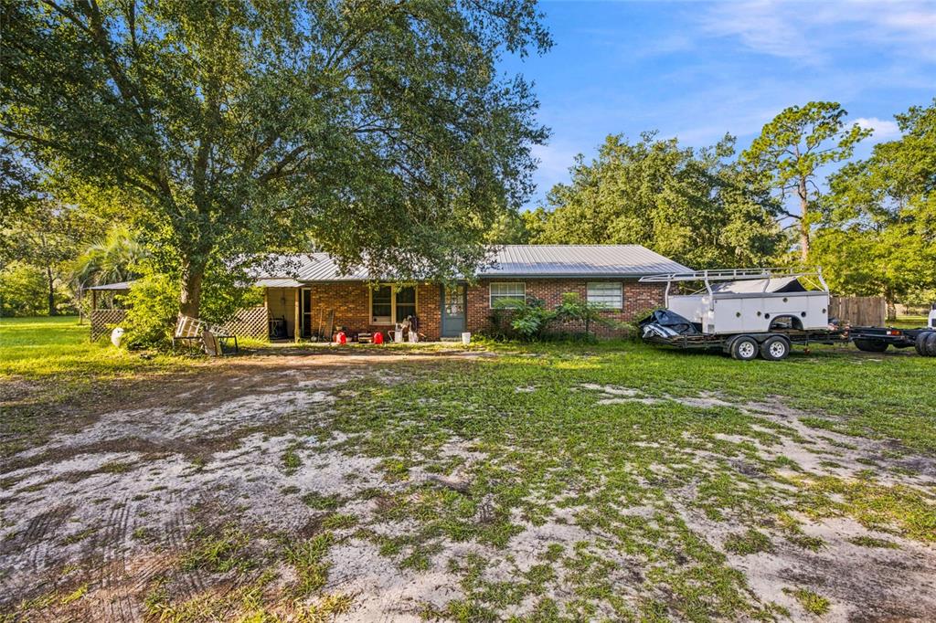 A single-story brick house with a metal roof sits on a large, grassy lot — 3025 S US HIGHWAY 41, DUNNELLON, FL