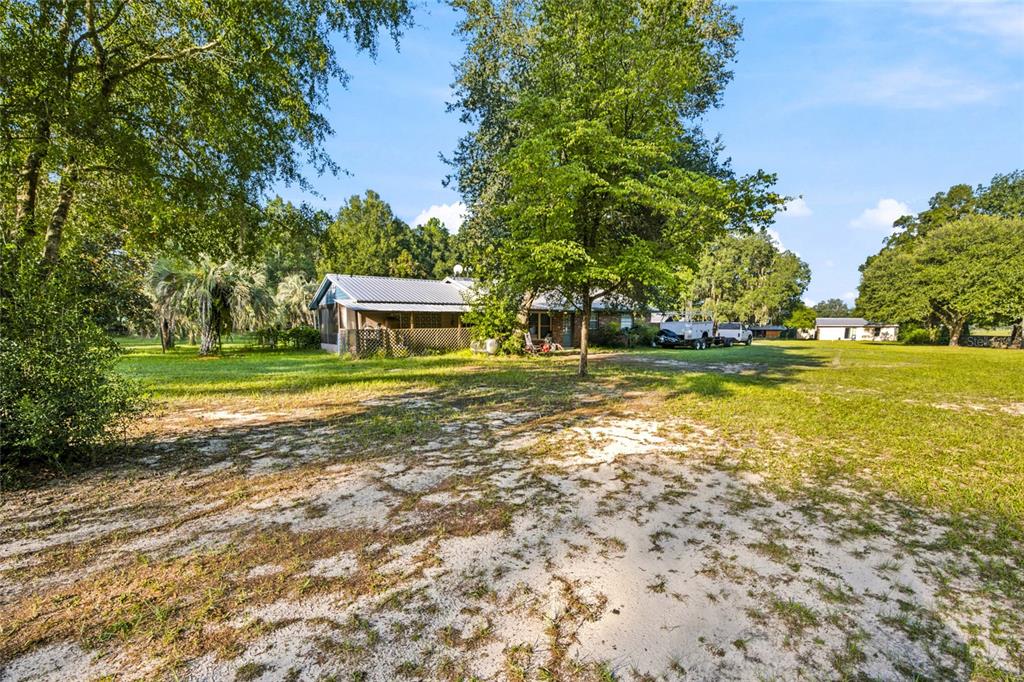 A single-story house with a metal roof sits on a large, grassy, sandy lot — 3025 S US HIGHWAY 41, DUNNELLON, FL
