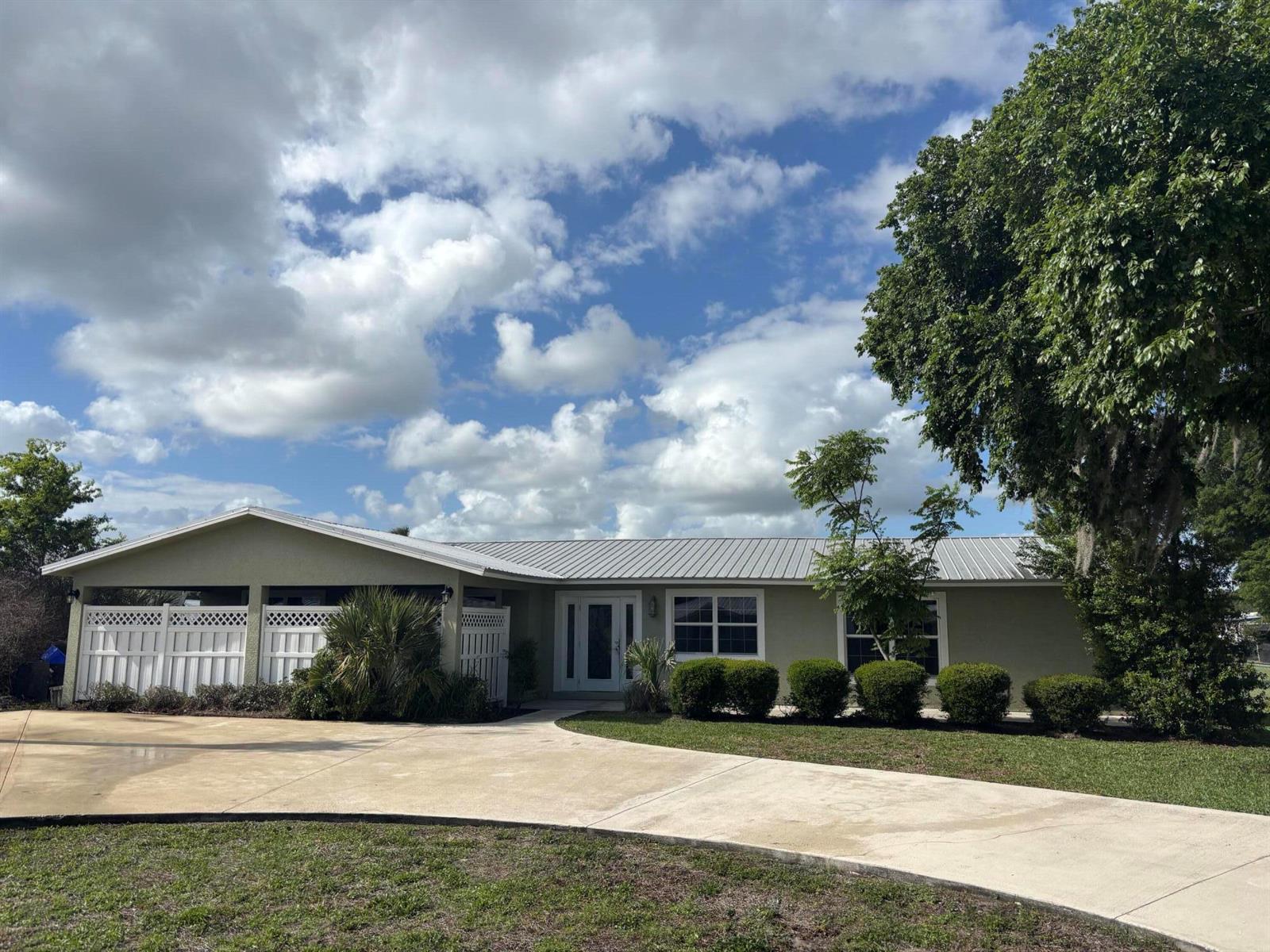 A single-story house with a metal roof, white privacy fencing, and a concrete driveway — 4003 SE 26th Street, Okeechobee FL 34974, OKEECHOBEE, FL