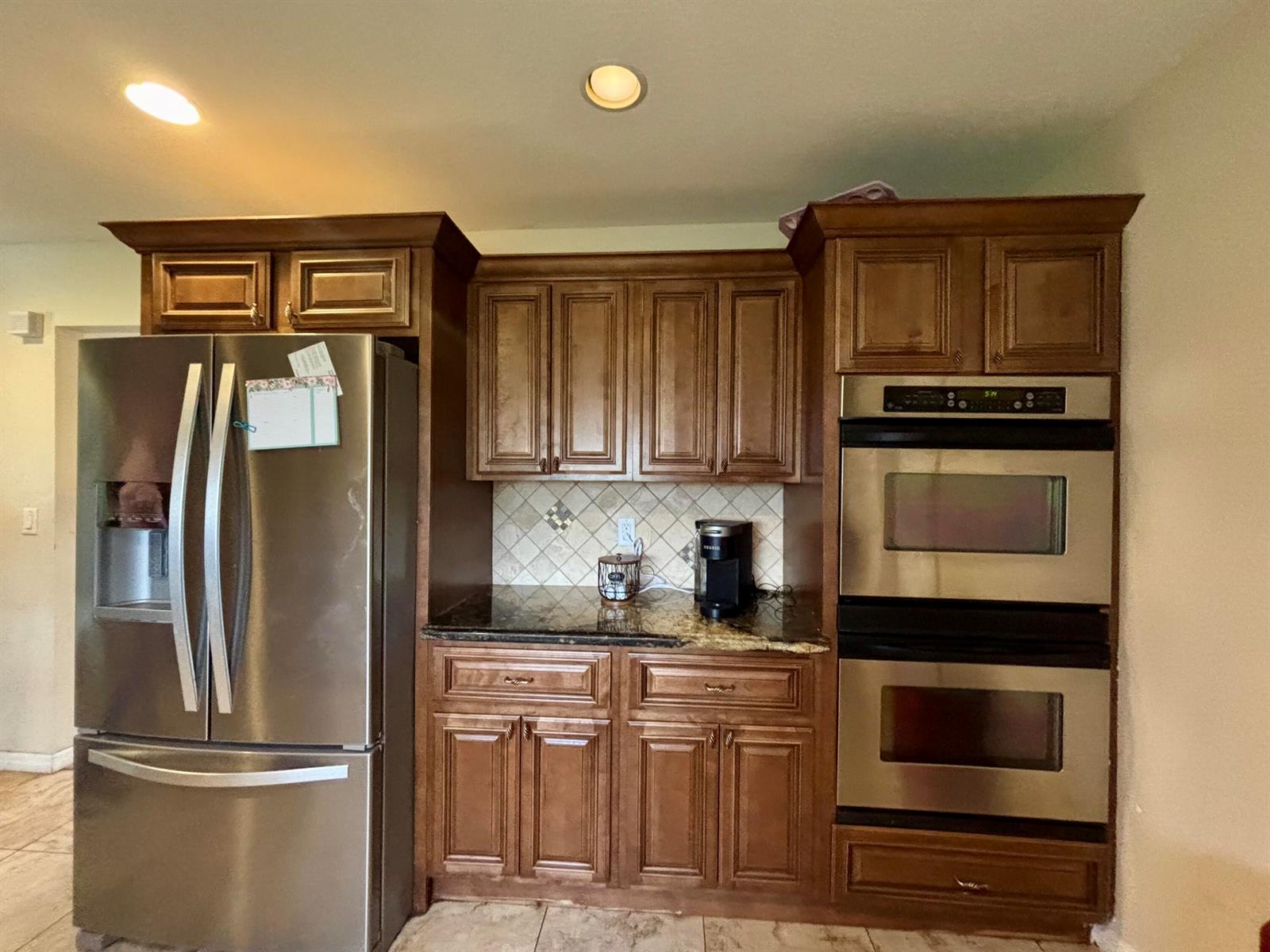 A kitchen features dark wood cabinets, stainless steel appliances, and a granite countertop — 4003 SE 26th Street, Okeechobee FL 34974, OKEECHOBEE, FL