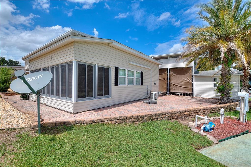 A beige mobile home features a screened-in porch, a brick paver patio, and a satellite dish — 2336 ST GEORGE DRIVE, DAVENPORT, FL