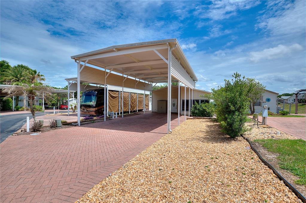 A large metal carport covers a paved driveway next to a manufactured home — 2336 ST GEORGE DRIVE, DAVENPORT, FL