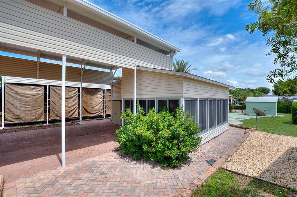 A paved patio area sits beside a screened-in porch and a covered carport structure — 2336 ST GEORGE DRIVE, DAVENPORT, FL