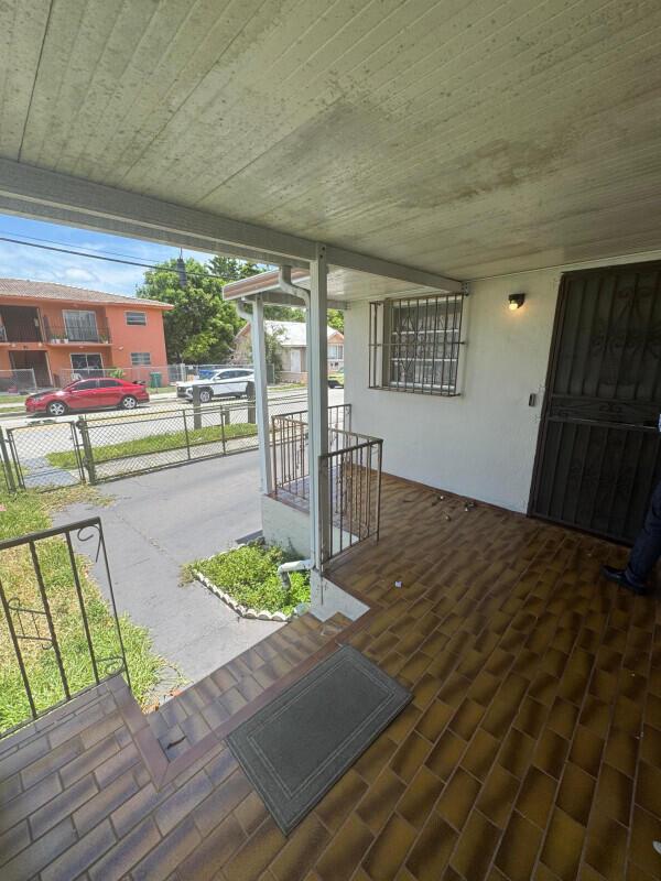 A covered porch with tiled flooring overlooks a residential street and a neighboring apartment building — 88 NW 18th Avenue, Miami FL 33125, MIAMI, FL