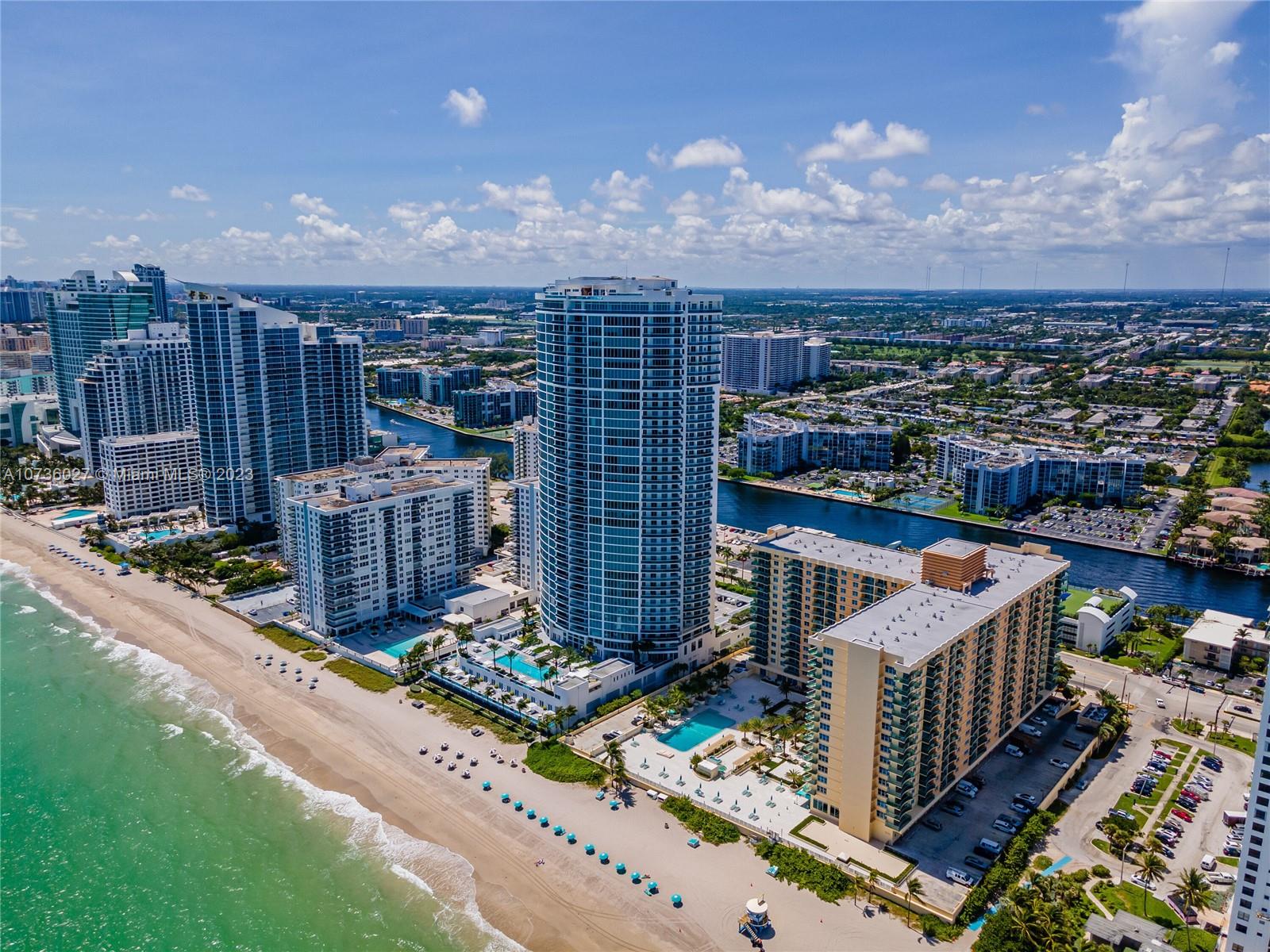 An aerial view of high-rise apartment buildings situated along a sandy beach and oceanfront — 2501 S OCEAN DR, Hollywood FL 33019, HOLLYWOOD, FL
