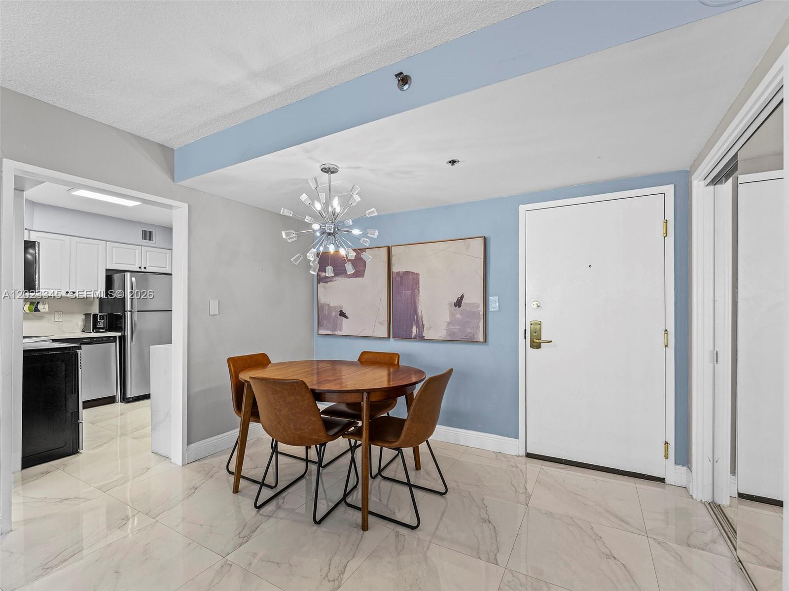 A dining area features a round wooden table, four chairs, and a modern sputnik chandelier — 5225 Collins Ave # 1509, Miami Beach FL 33140, MIAMI BEACH, FL