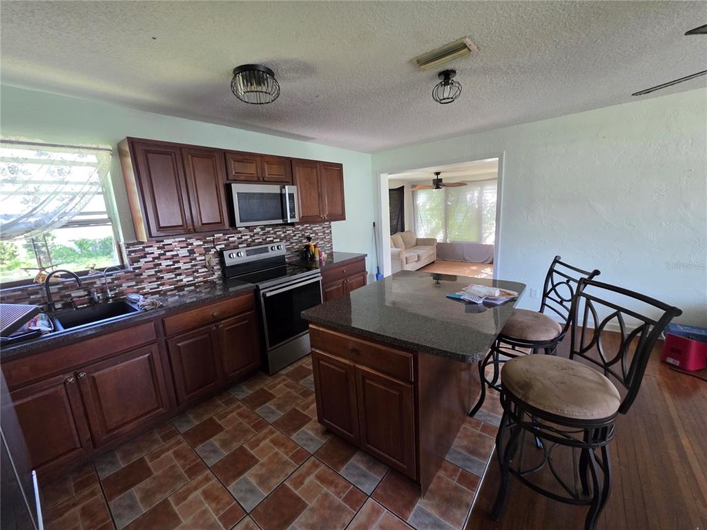 A kitchen with dark wood cabinets, a granite-topped island, and a tiled floor — 563 MARTHA DRIVE, HOLLY HILL, FL