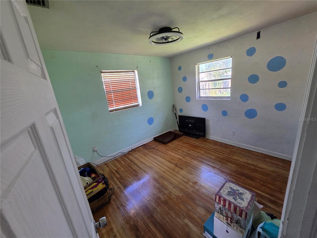 A bedroom with hardwood floors, light green walls featuring blue polka dots, and a window — 563 MARTHA DRIVE, HOLLY HILL, FL