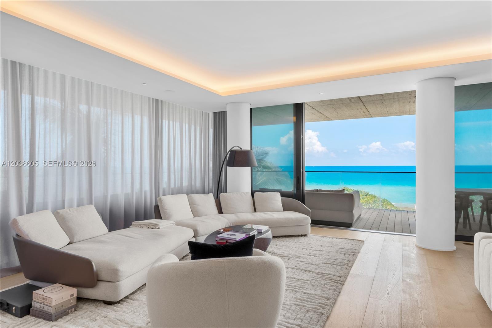 A modern living room features a large sectional sofa, floor-to-ceiling windows, and ocean views — 8955 E Collins Ave # 301, Surfside FL 33154, SURFSIDE, FL
