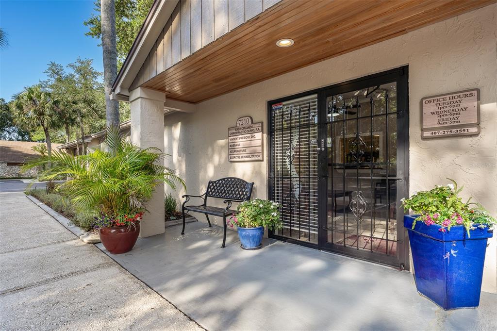 The exterior entrance of a chiropractic clinic features a bench, potted plants, and signage — 7210 CURRY FORD ROAD UNIT 2B, ORLANDO, FL