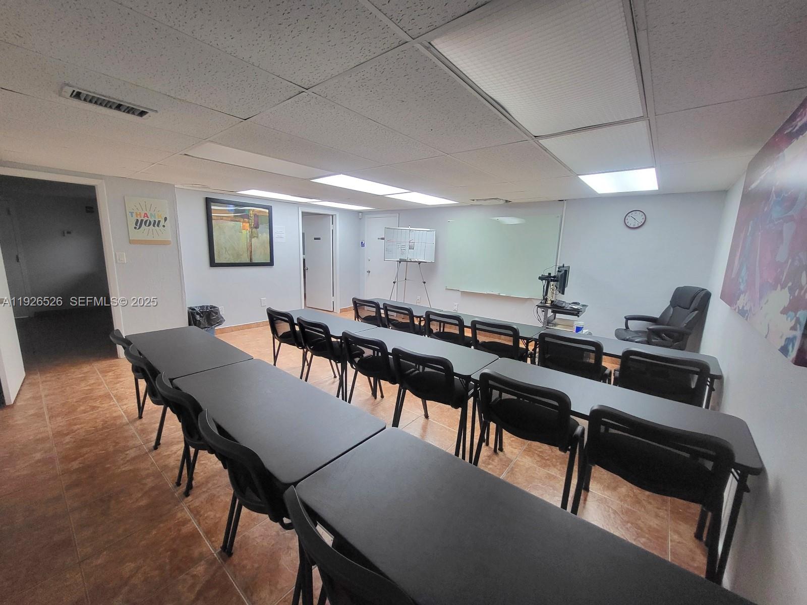 A classroom-style meeting room features rows of black tables and chairs facing a whiteboard — 13499 Biscayne Blvd, North Miami FL 33181, NORTH MIAMI, FL