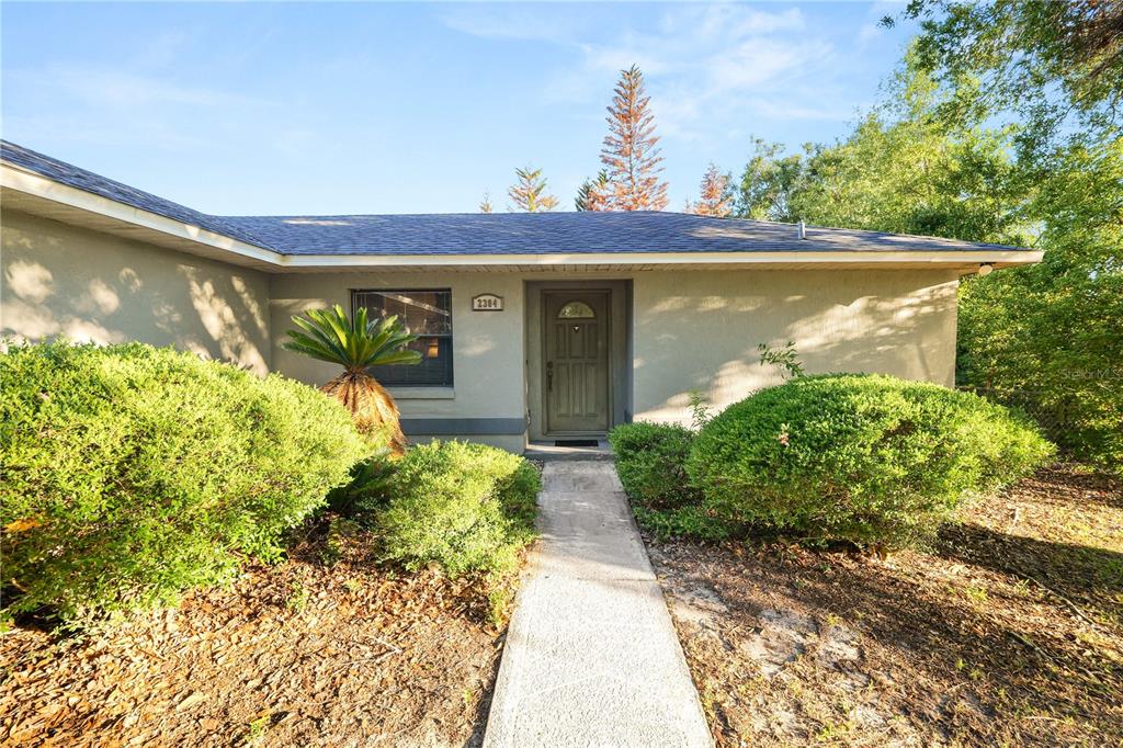 A single-story house with a concrete walkway leading to the front door and landscaping — 2304 CHESHIRE PLACE, LAKELAND, FL