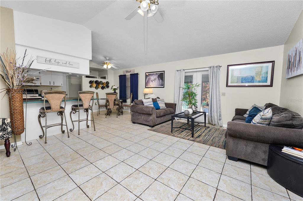 A living room with tile floors, two sofas, a dining area, and a breakfast bar — 2304 CHESHIRE PLACE, LAKELAND, FL