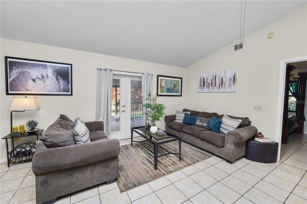 A living room features tile flooring, two brown sofas, a coffee table, and glass doors — 2304 CHESHIRE PLACE, LAKELAND, FL