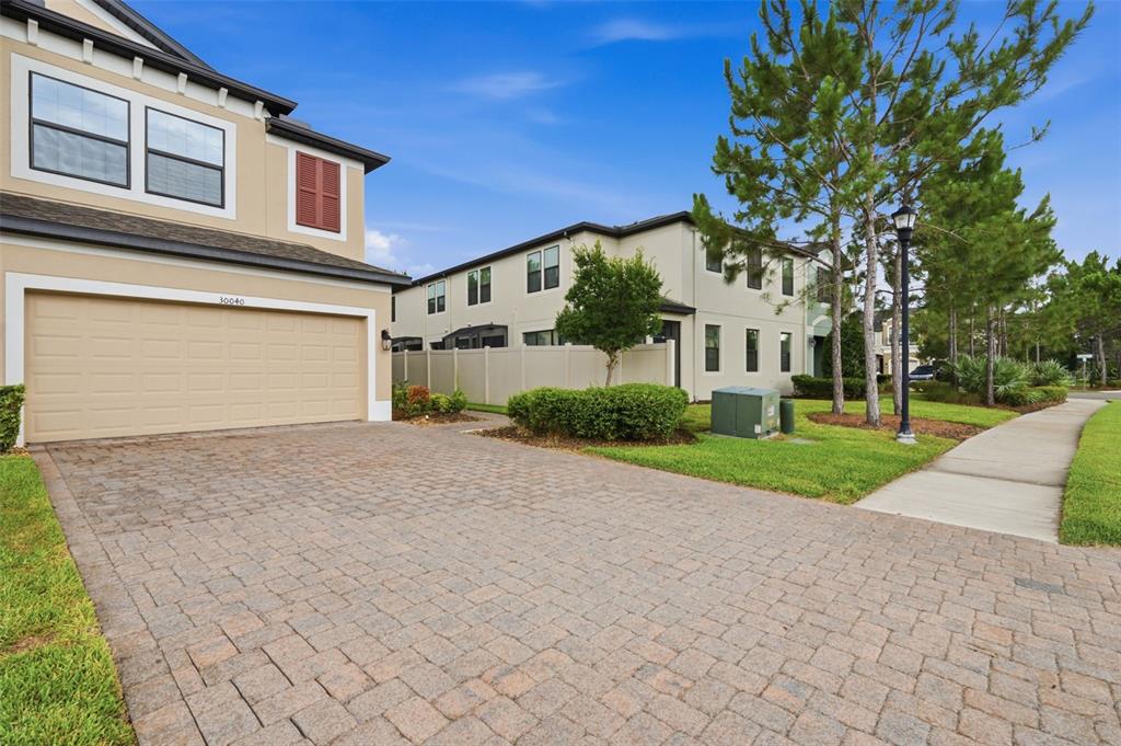A two-story house with a paved driveway and a two-car garage under a blue sky — 30040 SOUTHWELL LANE, WESLEY CHAPEL, FL