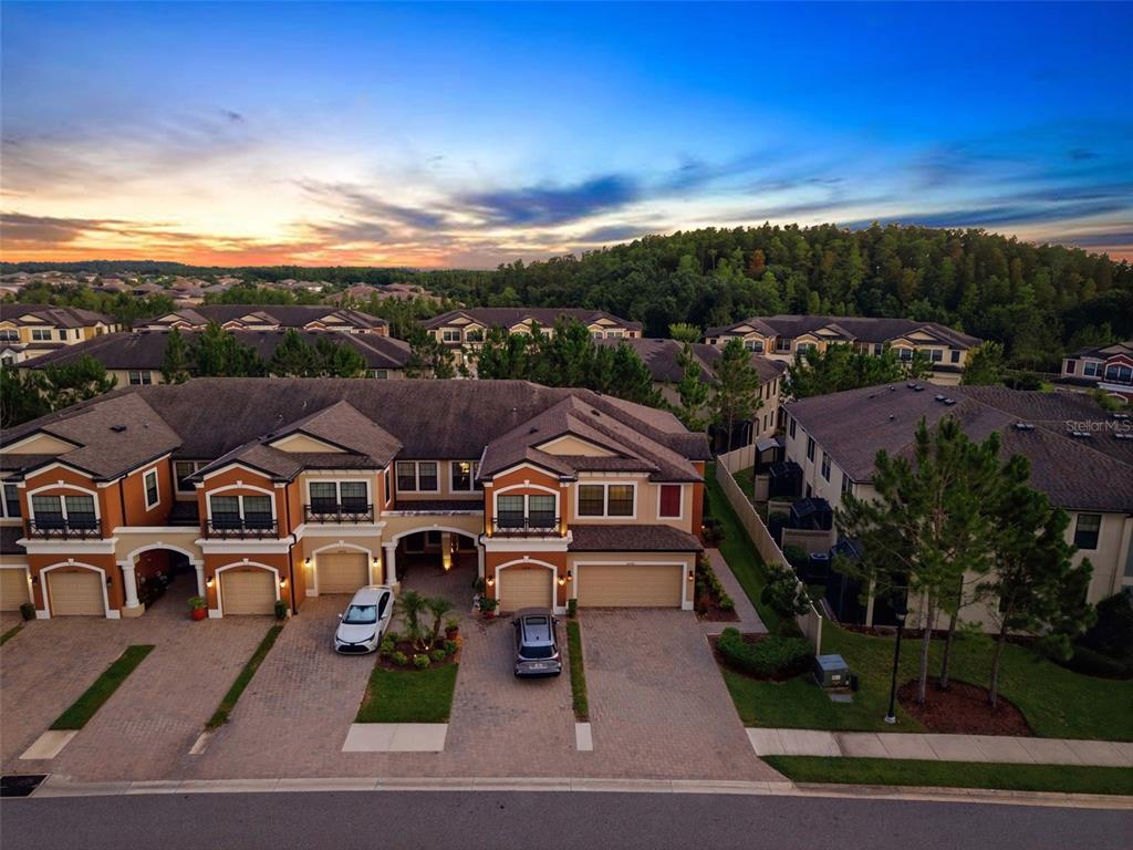 An aerial view of a multi-unit residential building with paved driveways at sunset — 30040 SOUTHWELL LANE, WESLEY CHAPEL, FL