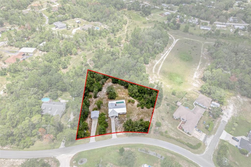 An aerial view shows a house and detached garage on a wooded lot — 7335 BLACKBIRD AVENUE, WEEKI WACHEE, FL