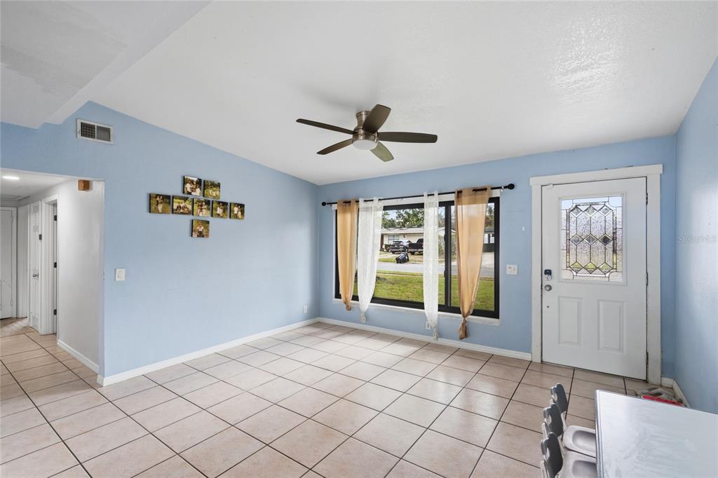 A living room with light blue walls, tile flooring, a ceiling fan, and a front door — 1307 BALTIMORE DRIVE, ORLANDO, FL