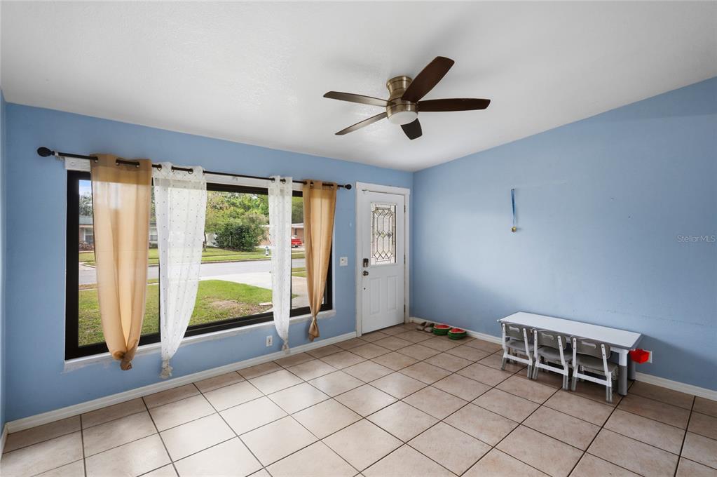A room with light blue walls, tile flooring, a ceiling fan, and a large window — 1307 BALTIMORE DRIVE, ORLANDO, FL