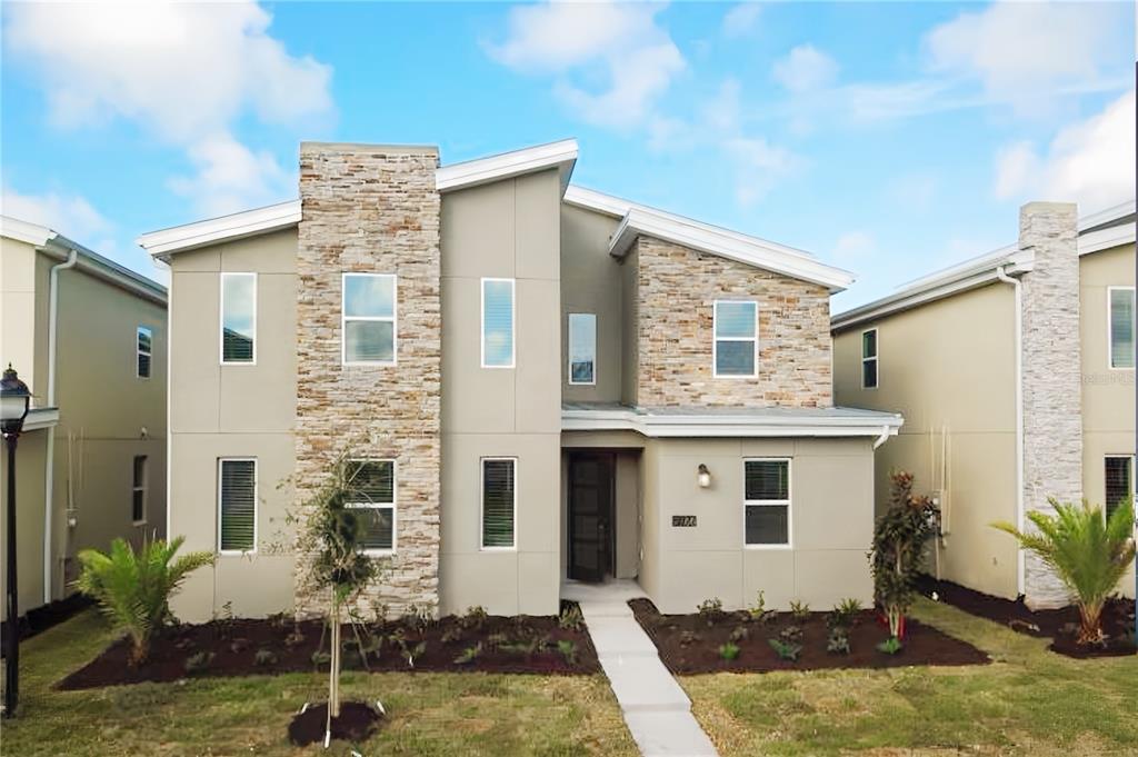 A two-story modern house with a stone facade, beige siding, and a concrete walkway — 2766 OXYMORON WAY, KISSIMMEE, FL