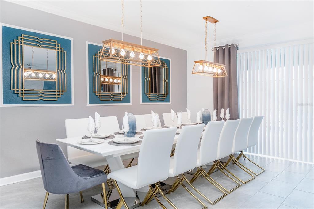 A dining room features a long white table, white chairs, and gold-framed mirrors on walls — 2766 OXYMORON WAY, KISSIMMEE, FL