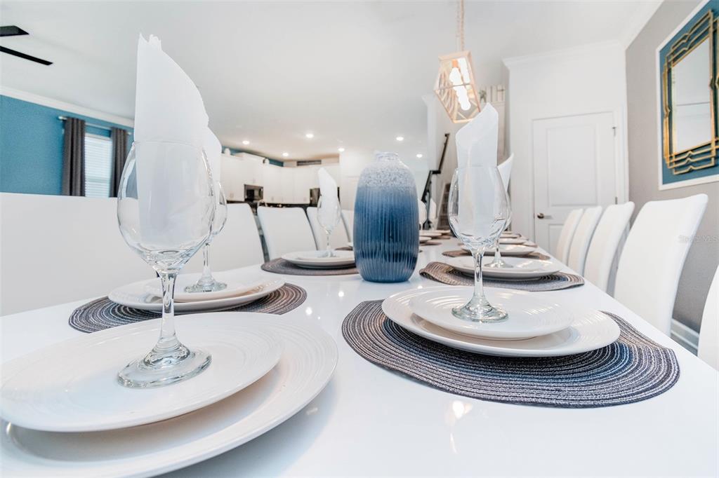 A dining room table is set with white plates, wine glasses, and blue placemats — 2766 OXYMORON WAY, KISSIMMEE, FL