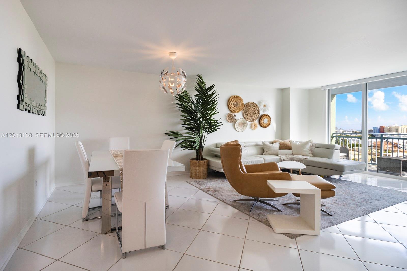 A bright, open-concept living and dining area features white tile floors and a balcony view — 90 Alton Rd # 1005, Miami Beach FL 33139, MIAMI BEACH, FL
