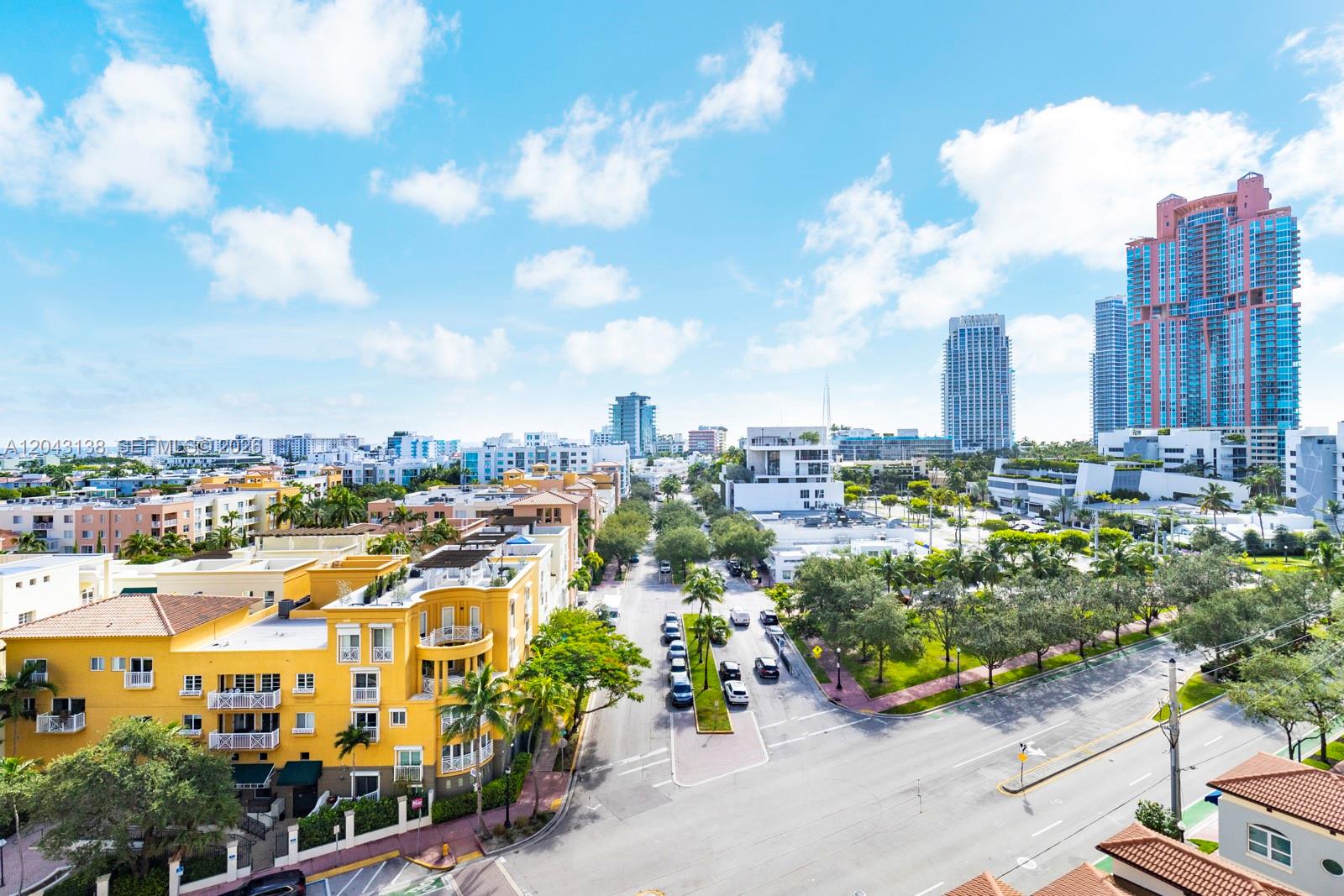 An elevated view of a city street lined with yellow buildings, trees, and skyscrapers — 90 Alton Rd # 1005, Miami Beach FL 33139, MIAMI BEACH, FL