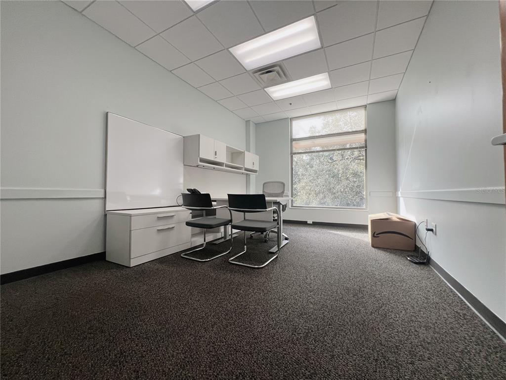 An office with a desk, chairs, white cabinets, a whiteboard, and a large window — 800 CELEBRATION AVENUE UNIT 201-F, CELEBRATION, FL