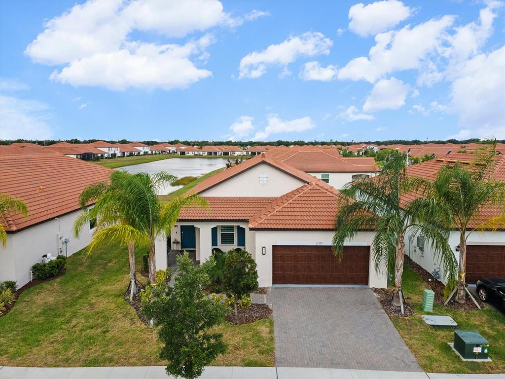 An aerial view of a single-story house with a tile roof and a paved driveway — 17127 HOLLY WELL AVENUE, WIMAUMA, FL