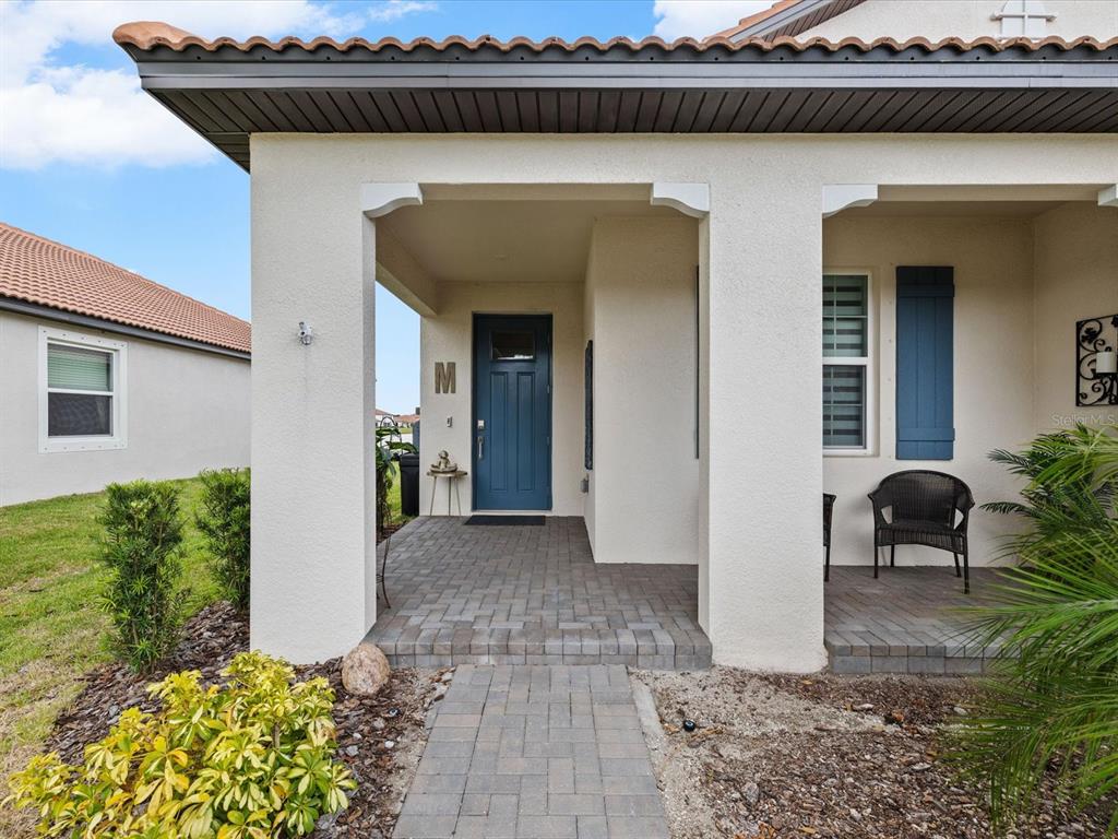 A covered front porch with brick pavers leads to a blue front door — 17127 HOLLY WELL AVENUE, WIMAUMA, FL