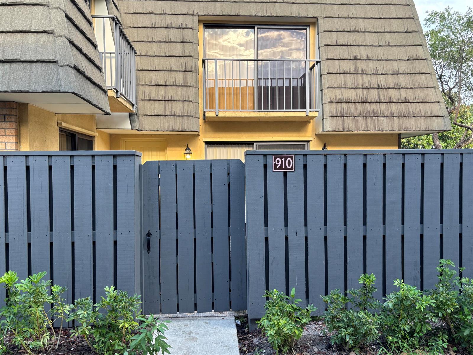 A gray wooden fence with a gate stands in front of a two-story residential building — 910 9th Way, West Palm Beach FL 33407, WEST PALM BEACH, FL