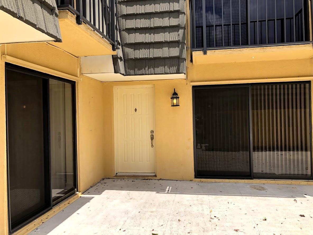 A yellow stucco exterior features a central front door flanked by two sliding glass doors — 910 9th Way, West Palm Beach FL 33407, WEST PALM BEACH, FL