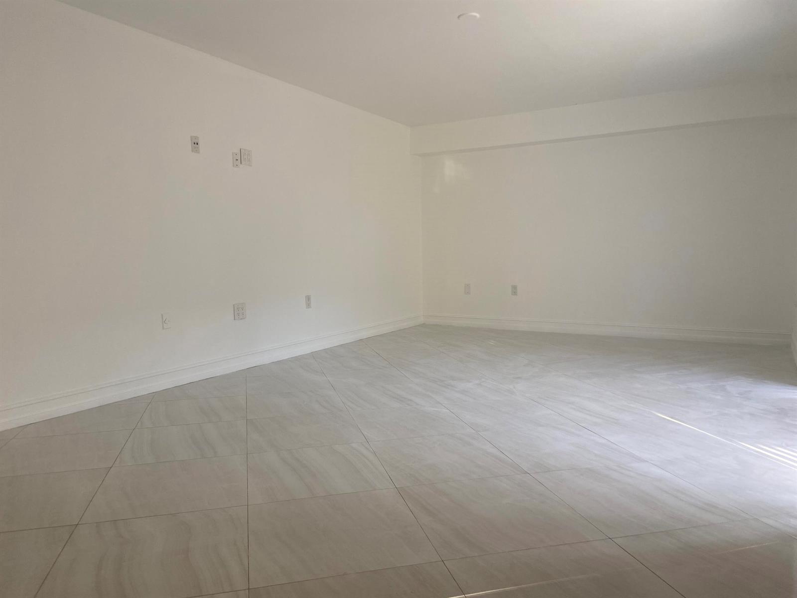 An empty room features white walls, light-colored tile flooring, and multiple electrical outlets — 910 9th Way, West Palm Beach FL 33407, WEST PALM BEACH, FL