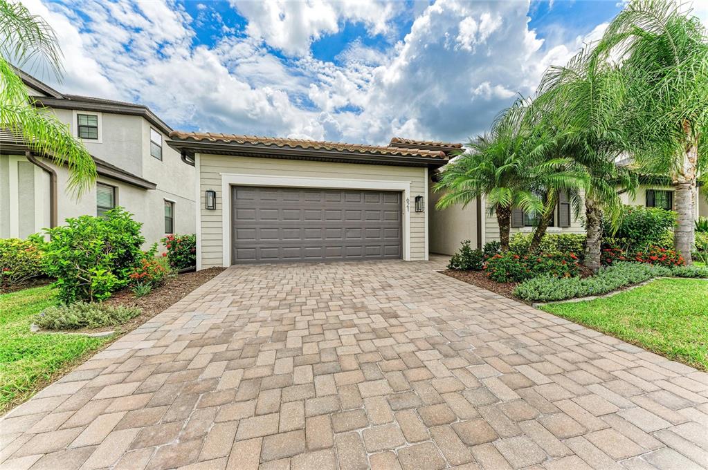 A paved driveway leads to the garage of a single-story house with palm trees — 621 FIRE BUSH COURT, BRADENTON, FL