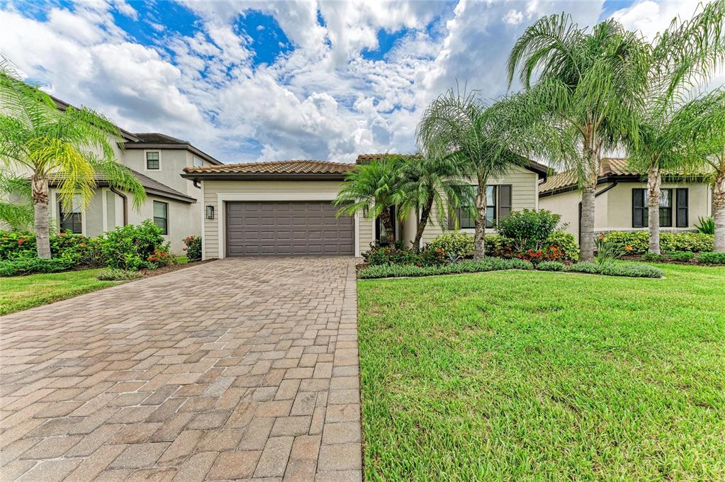 A single-story house with a paved driveway, a two-car garage, and palm trees in front — 621 FIRE BUSH COURT, BRADENTON, FL