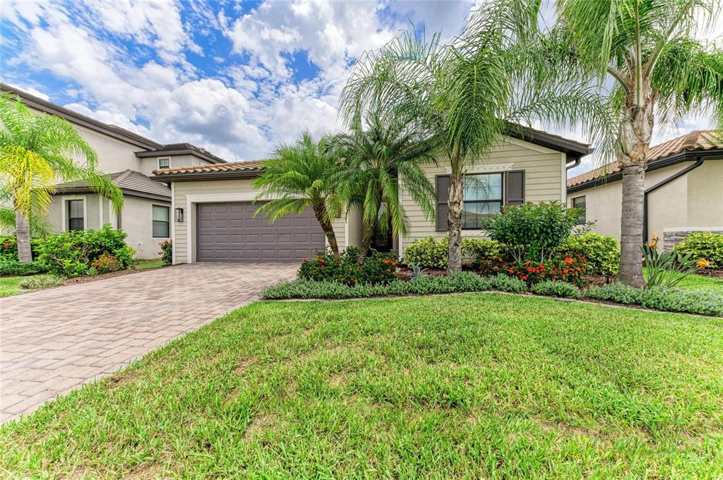 A single-story house with a paved driveway, a two-car garage, and palm trees in front — 621 FIRE BUSH COURT, BRADENTON, FL