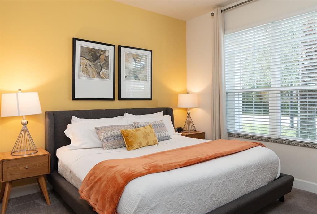 A bedroom features a gray upholstered bed, yellow accent wall, and two bedside lamps — 1653 RETREAT CIRCLE, CLERMONT, FL