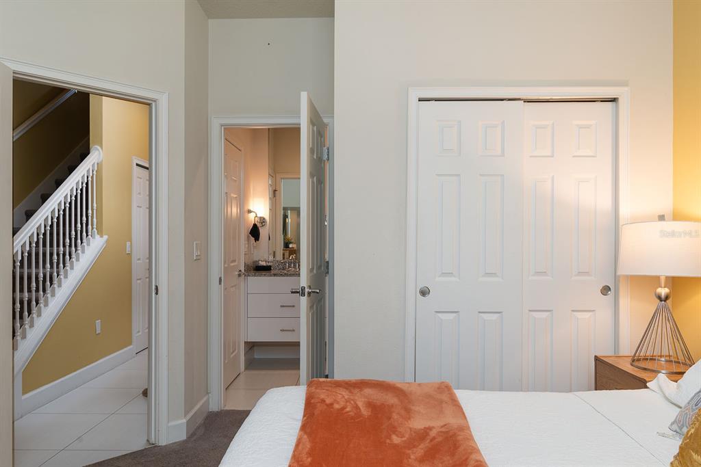 A bedroom features a closet, an open doorway to a bathroom, and a staircase view — 1653 RETREAT CIRCLE, CLERMONT, FL