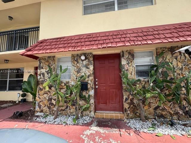 The exterior of a building features a red door, stone siding, and a red shingled roof — 6631 SW 41st Pl # 43, Davie FL 33314, DAVIE, FL
