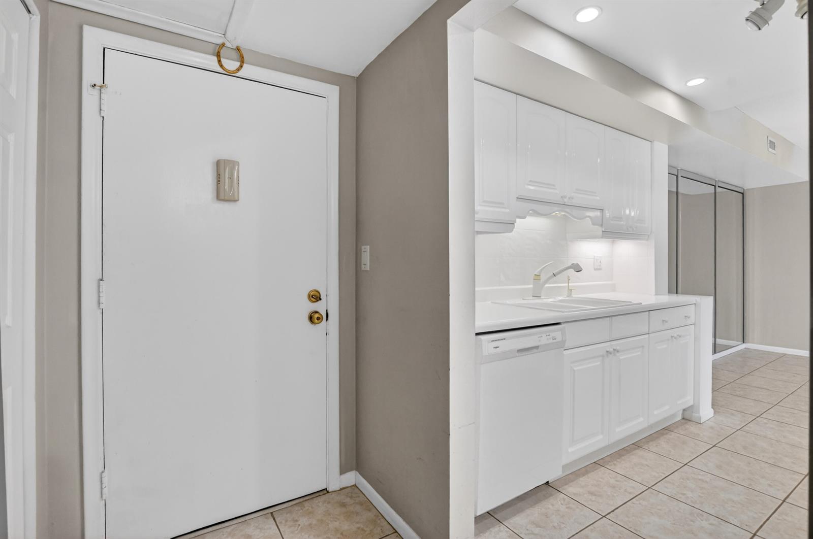 A white front door sits next to a small kitchen with white cabinets and appliances — 250 NE 20th Street # 5220, Boca Raton FL 33431, BOCA RATON, FL