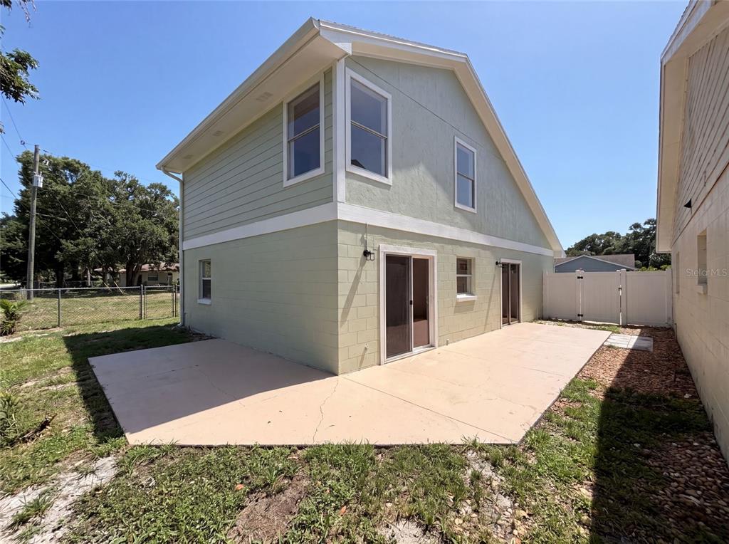 The exterior of a two-story house features light green siding, a concrete patio, and sliding doors — 1030 MARTIN BOULEVARD UNIT 1, ORLANDO, FL