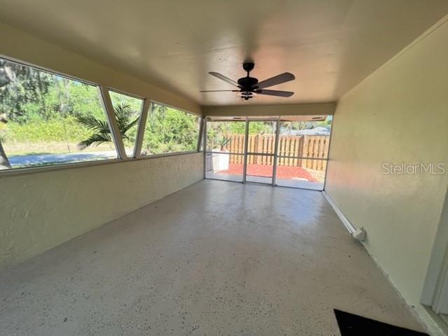 A screened-in porch with a ceiling fan, concrete flooring, and large windows overlooking a yard — 424 VANNELL STREET, PORT CHARLOTTE, FL
