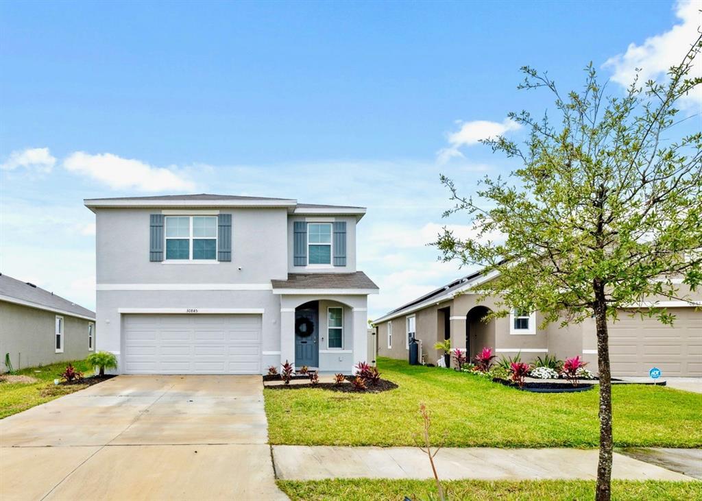 A two-story gray house with a two-car garage and a front lawn — 30845 PENNY SURF LOOP, WESLEY CHAPEL, FL