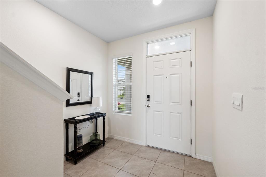 An entryway with tile flooring, a white front door, a console table, and a mirror — 30845 PENNY SURF LOOP, WESLEY CHAPEL, FL