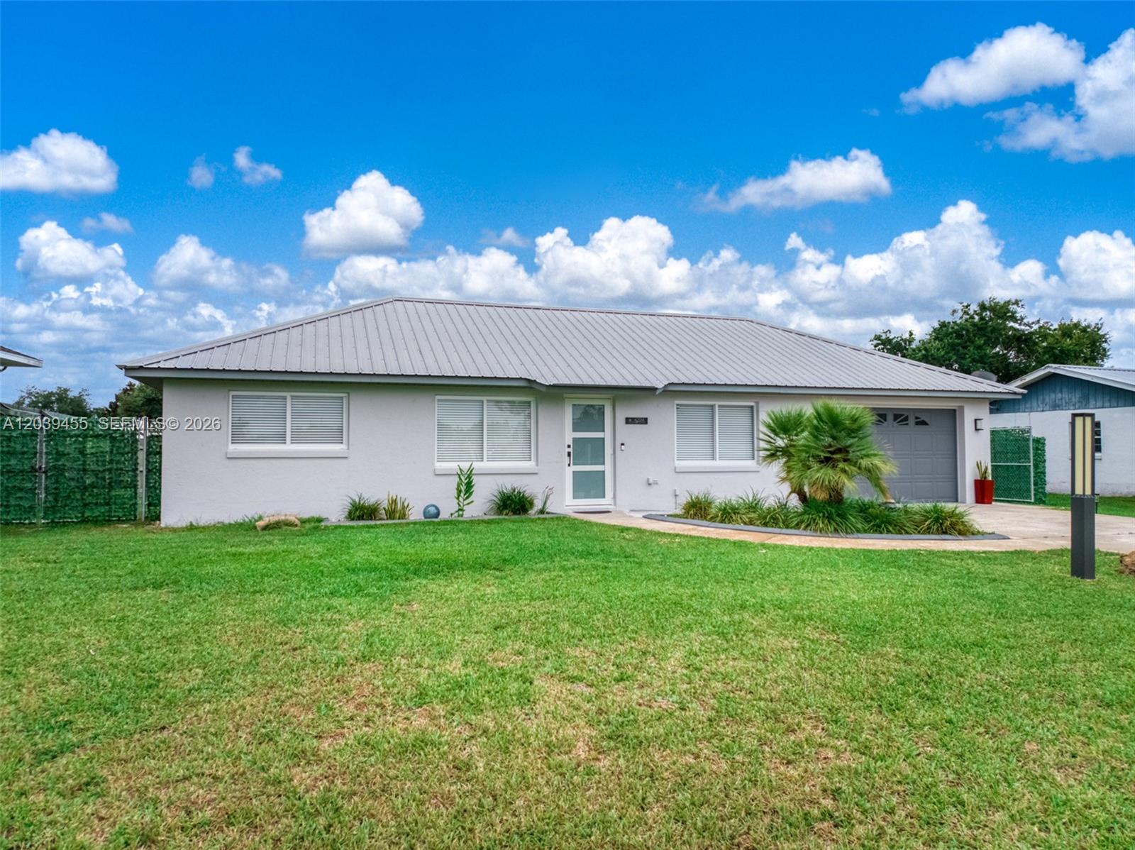 A single-story house with a gray metal roof, light-colored exterior, and a front lawn — 4224 Lake Vista, Sebring FL 33875, SEBRING, FL