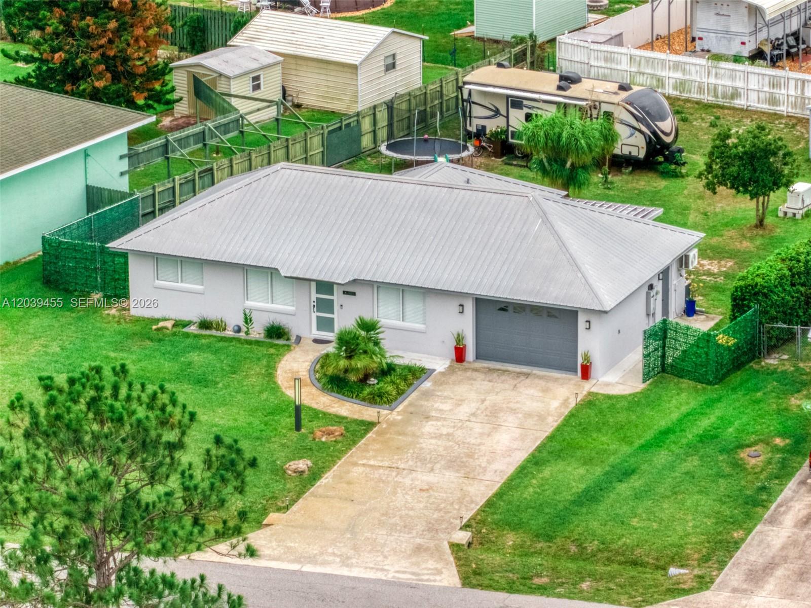 An aerial view of a single-story house with a metal roof and a concrete driveway — 4224 Lake Vista, Sebring FL 33875, SEBRING, FL