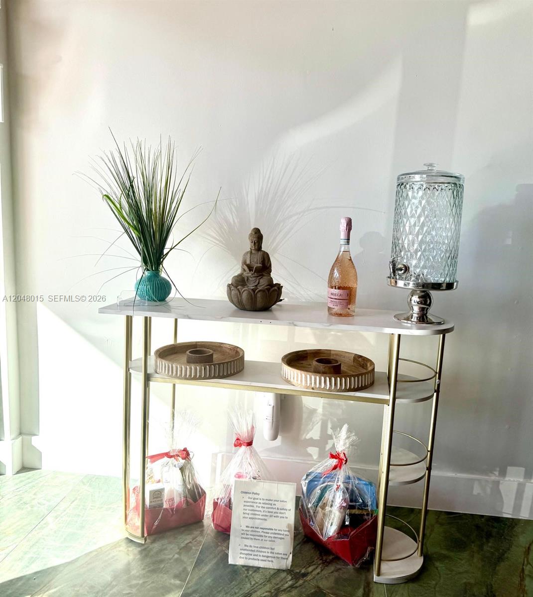 A white marble console table with gold legs displays a plant, statue, bottle, and dispenser — 18710 SW 107 ave, Miami FL 33157, MIAMI, FL